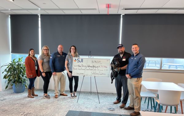 people posing for picture in front of large check